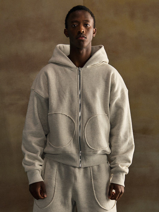 Person wearing a gray hoodie and pants set against a brown background